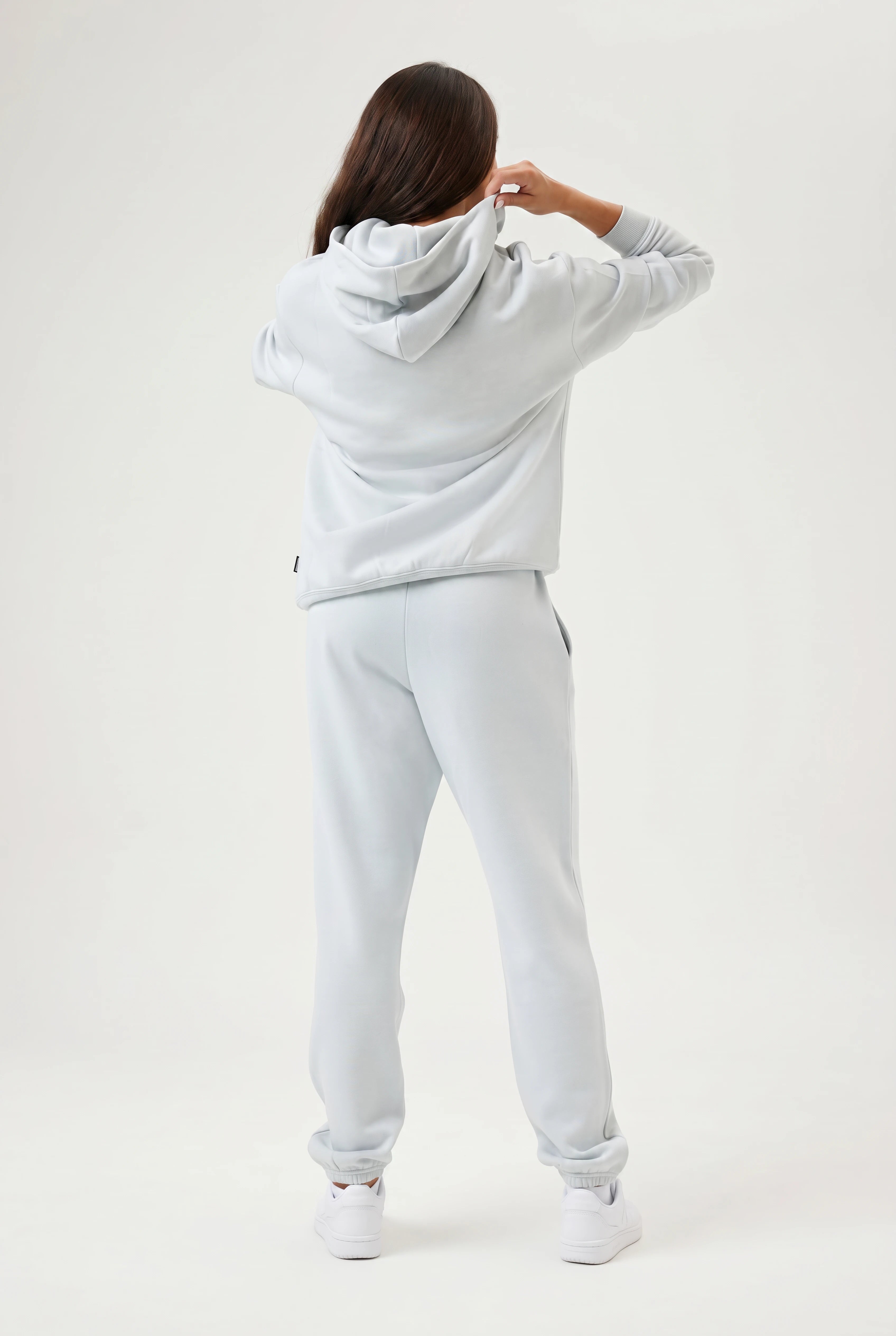 Person wearing a light blue hoodie and pants on a white background