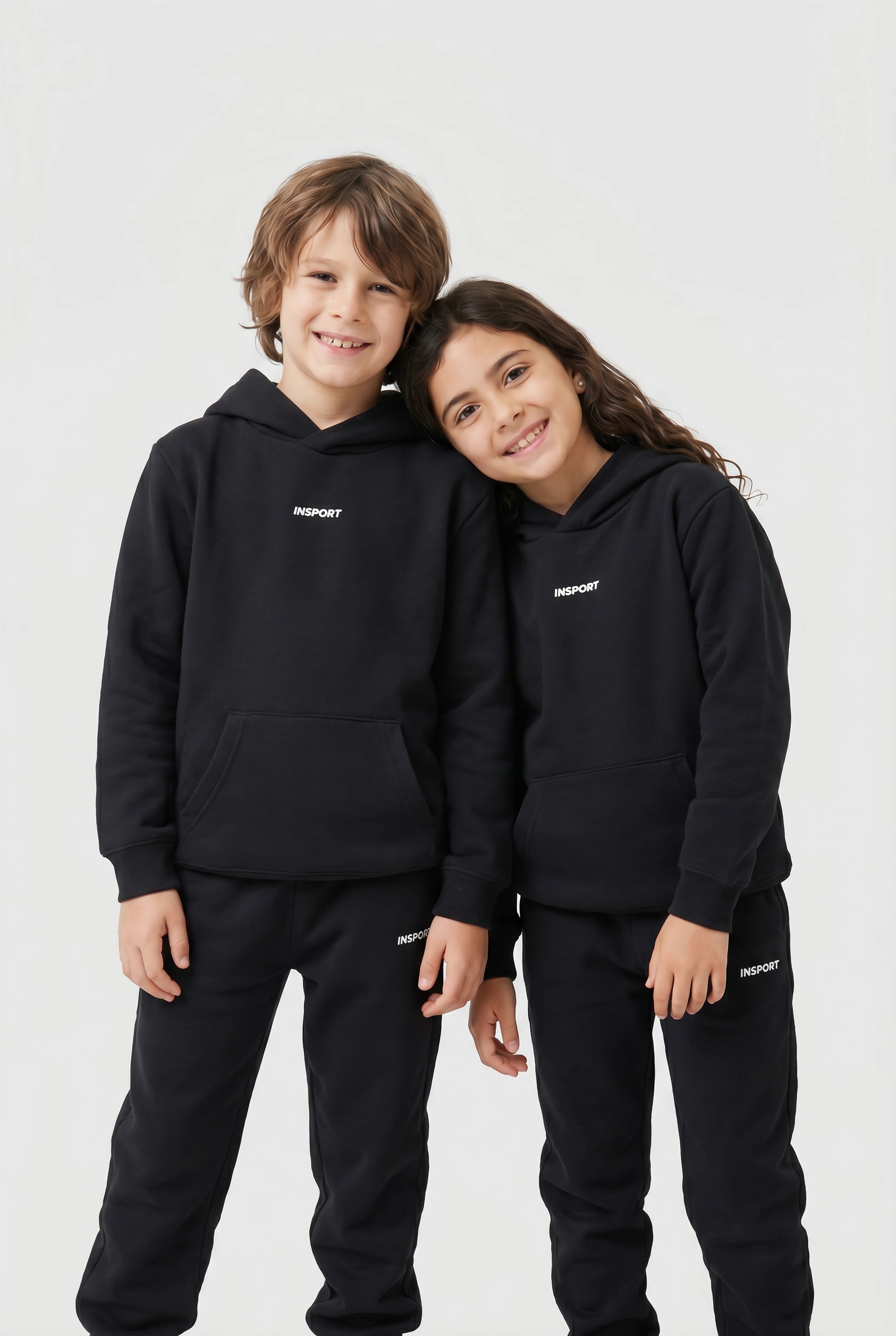 Two children wearing black hoodies with a brand logo on a white background
