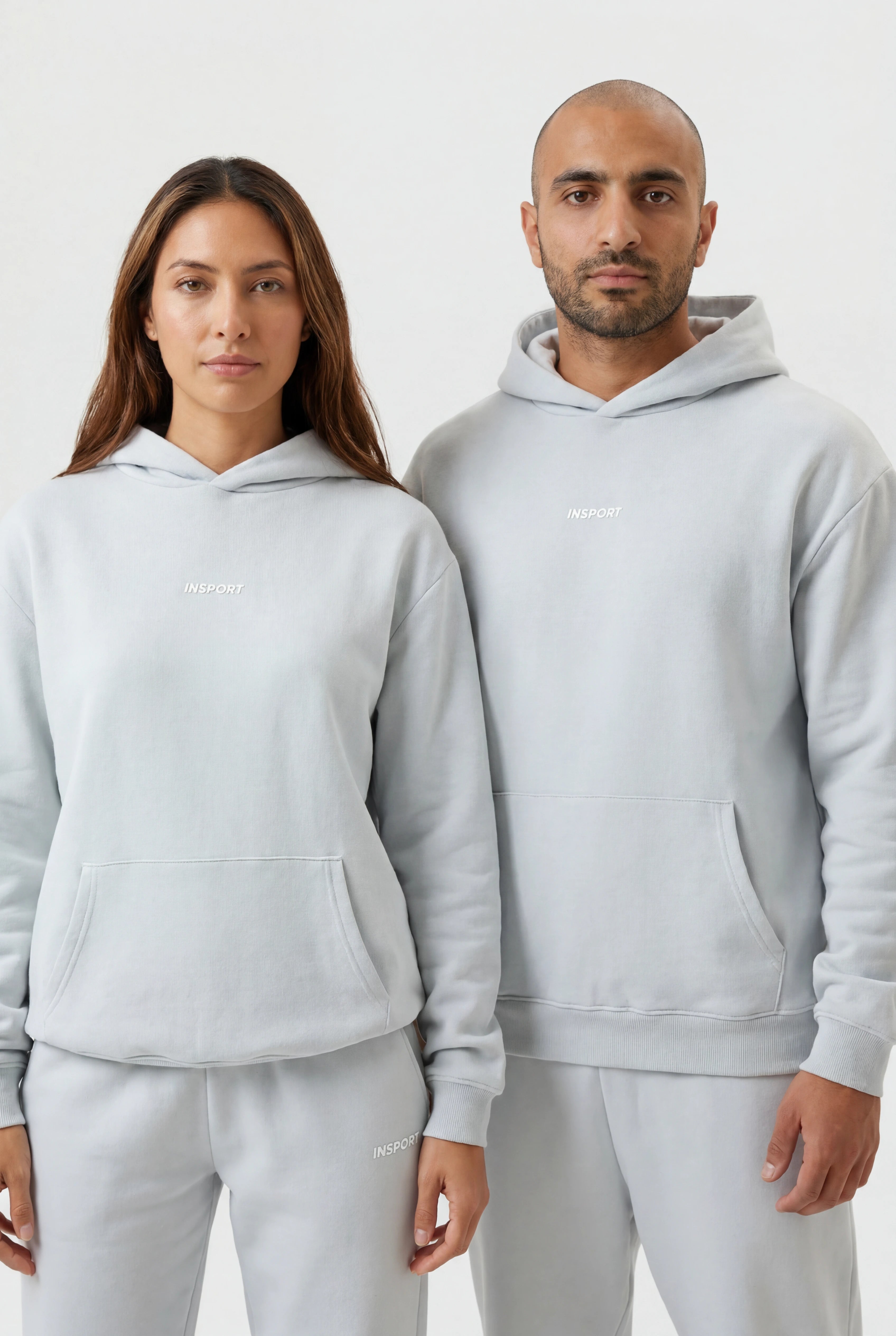 Two people wearing matching blue hoodies and pants on a white background