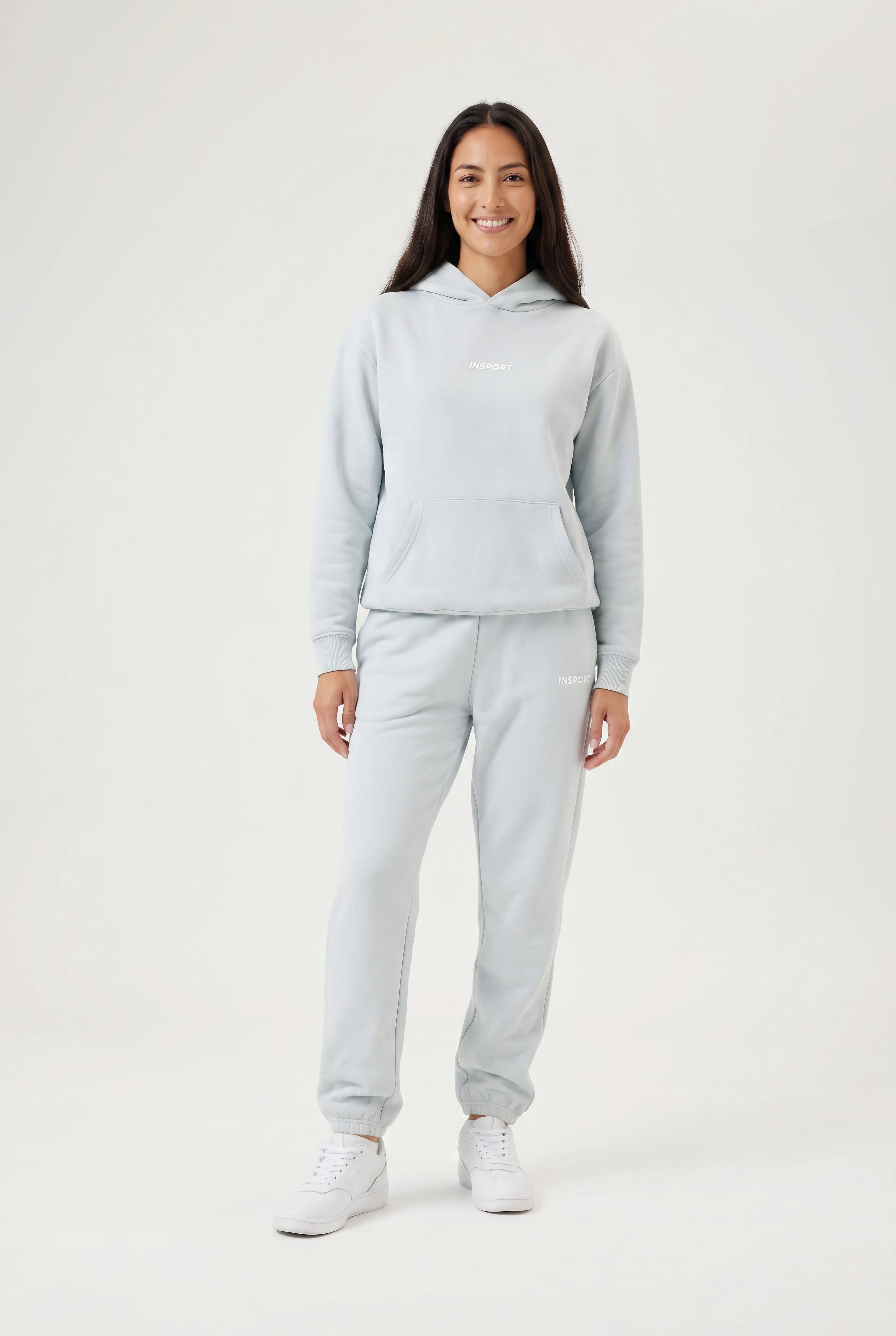 Person wearing a light blue hoodie and pants set on a white background
