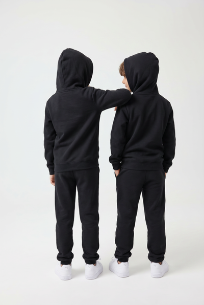 Two people wearing black hoodies and pants on a white background