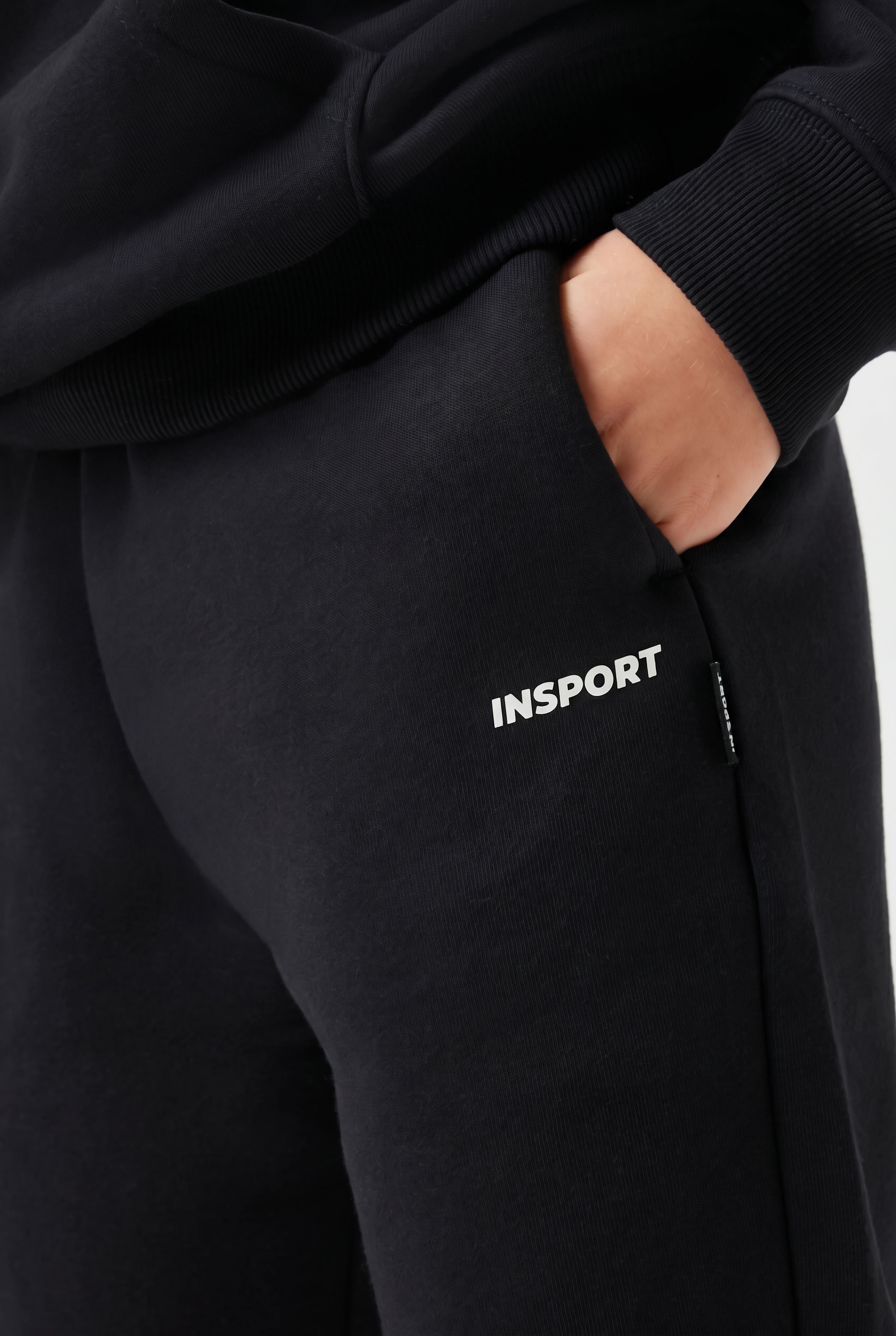 Black tracksuit with 'INSPORT' logo on the pocket against a neutral background