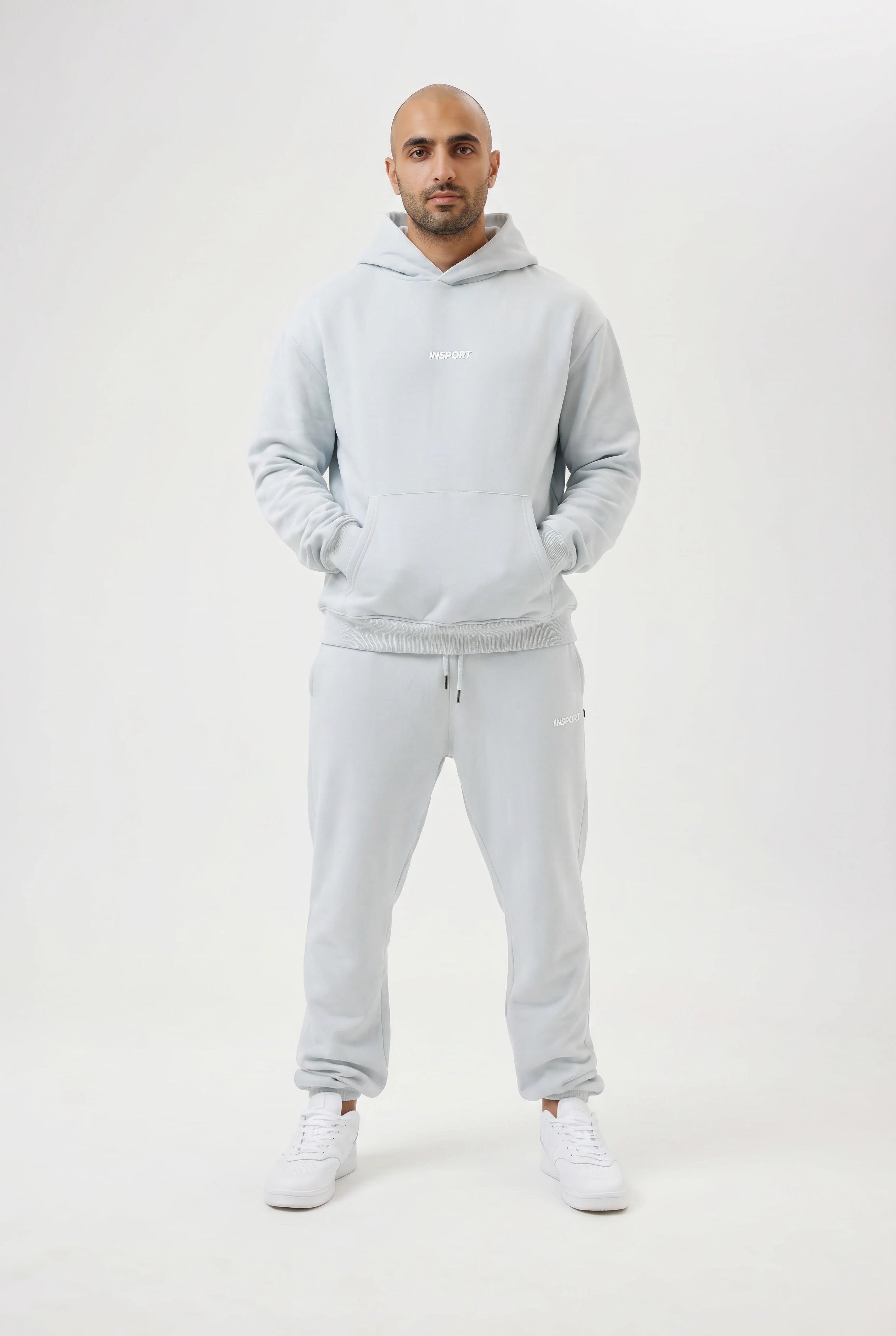 Man wearing a light blue hoodie and pants set on a white background