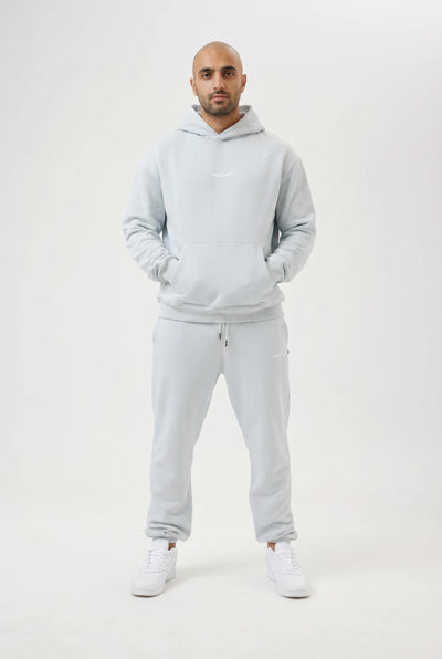 Man wearing a light blue hoodie and pants set on a white background