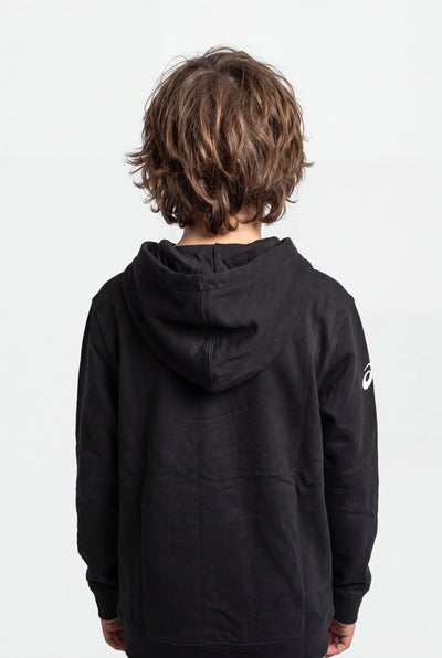 A child viewed from behind wearing a black hooded sweatshirt with a small white Asics logo on the left sleeve, set against a plain light gray studio background.
