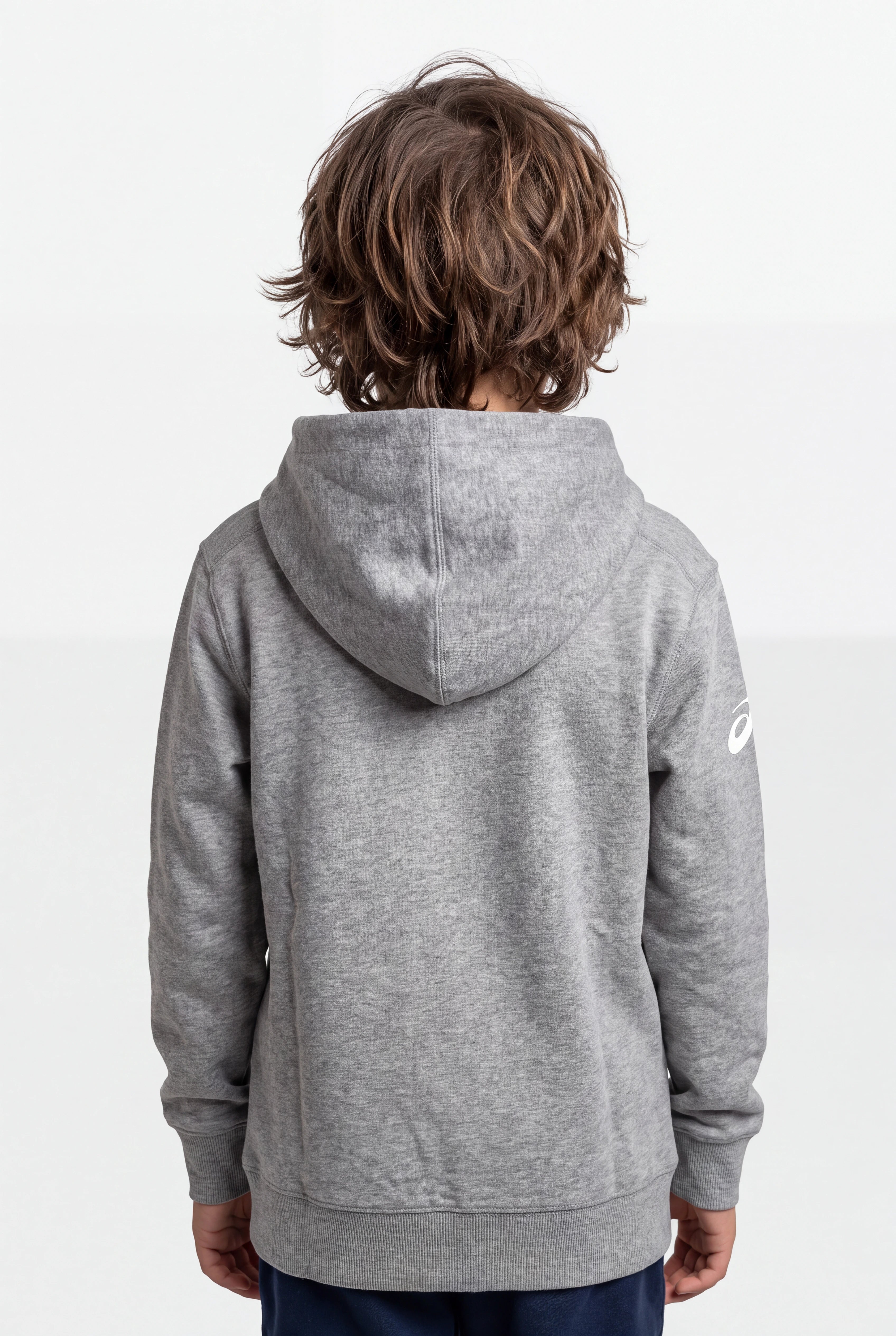 A child viewed from behind wearing a heather gray hooded sweatshirt with a small white Asics logo on the left sleeve, set against a plain light gray studio background.