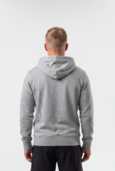 A man viewed from behind wearing a heather gray pullover hoodie and black athletic shorts, standing against a plain white studio background.